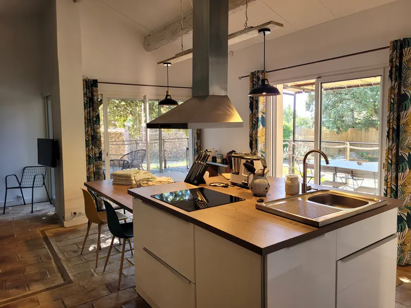 Cuisine du gîte avec îlot central et baies vitrées ouvertes sur la terrasse